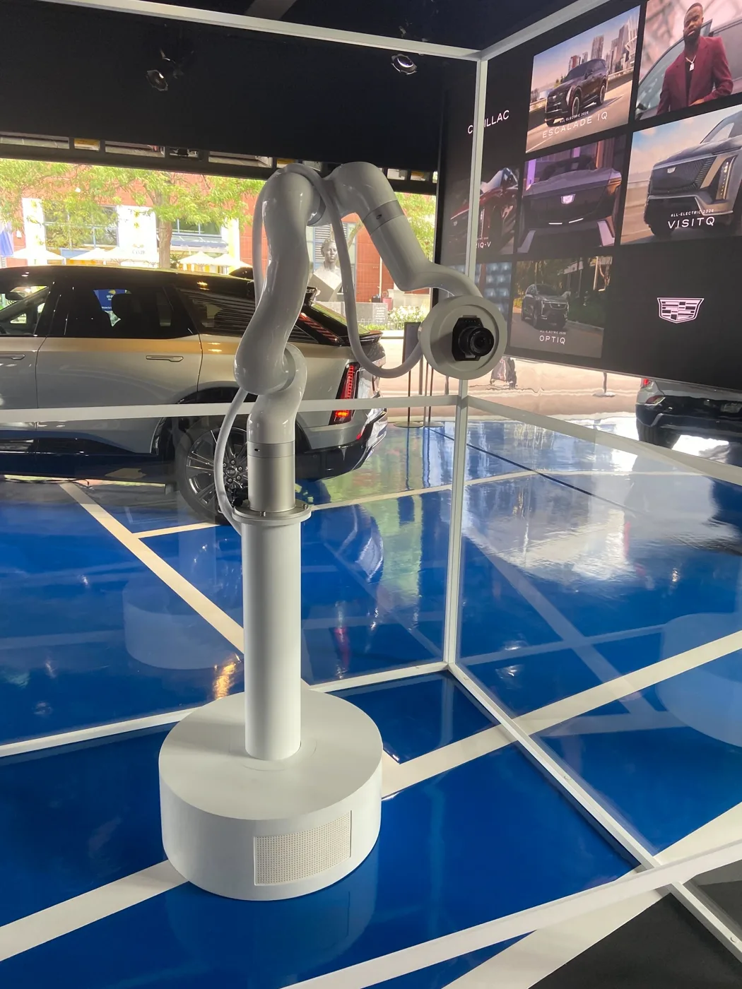 The arm with the camera mounted on its end effector, Cadillac vehicles behind